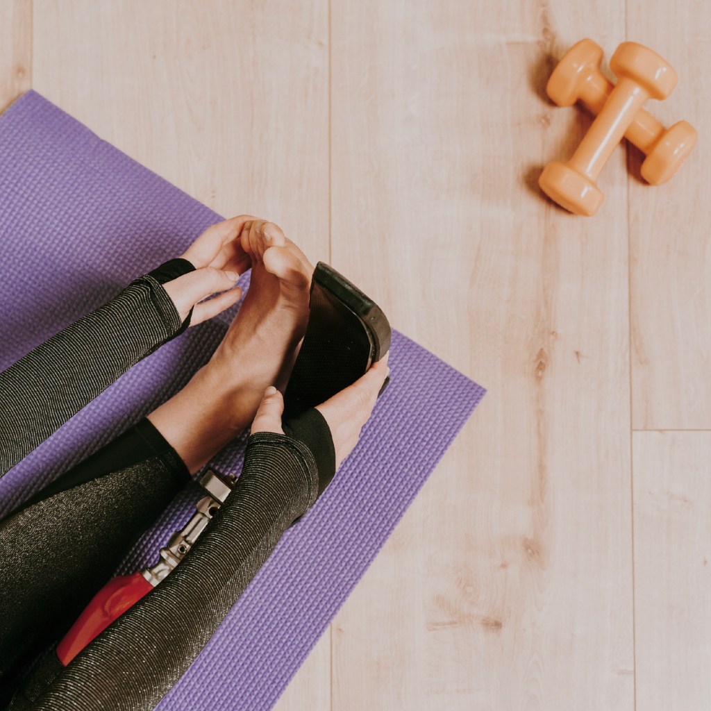A person stretching on a yoga mat, symbolizing the importance of exercise in self-care.
