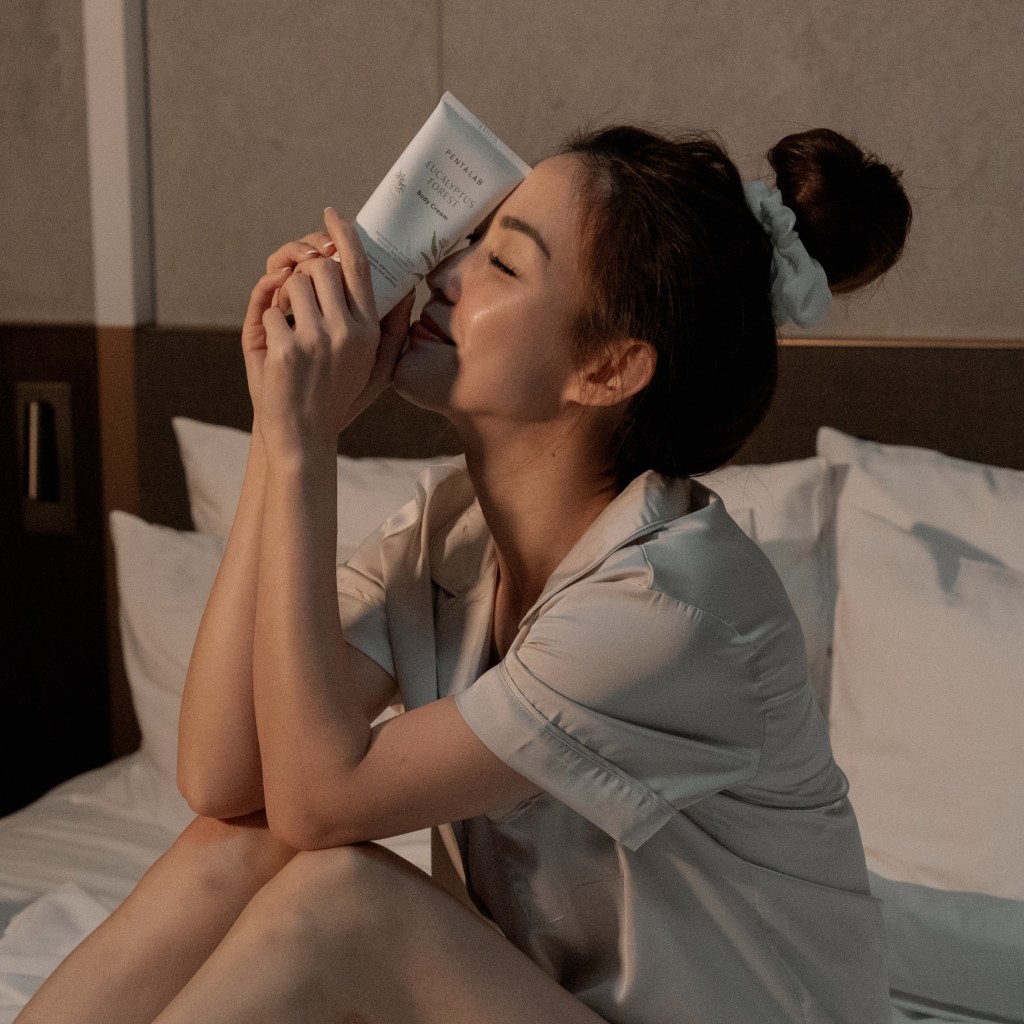 Woman holding Eucalyptus Forest Body Cream before sleep for nighttime skin repair.